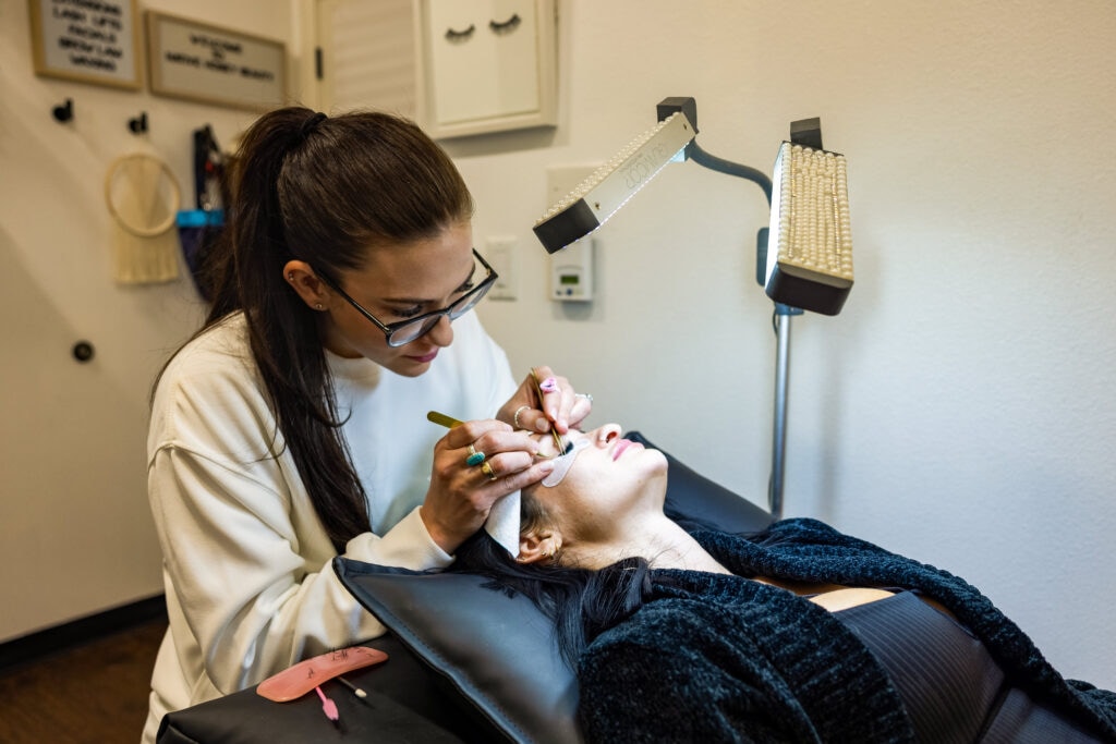 Beauty technician applying eyelash extensions to client