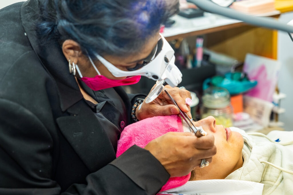 Technician applying eyelash extensions on client.
