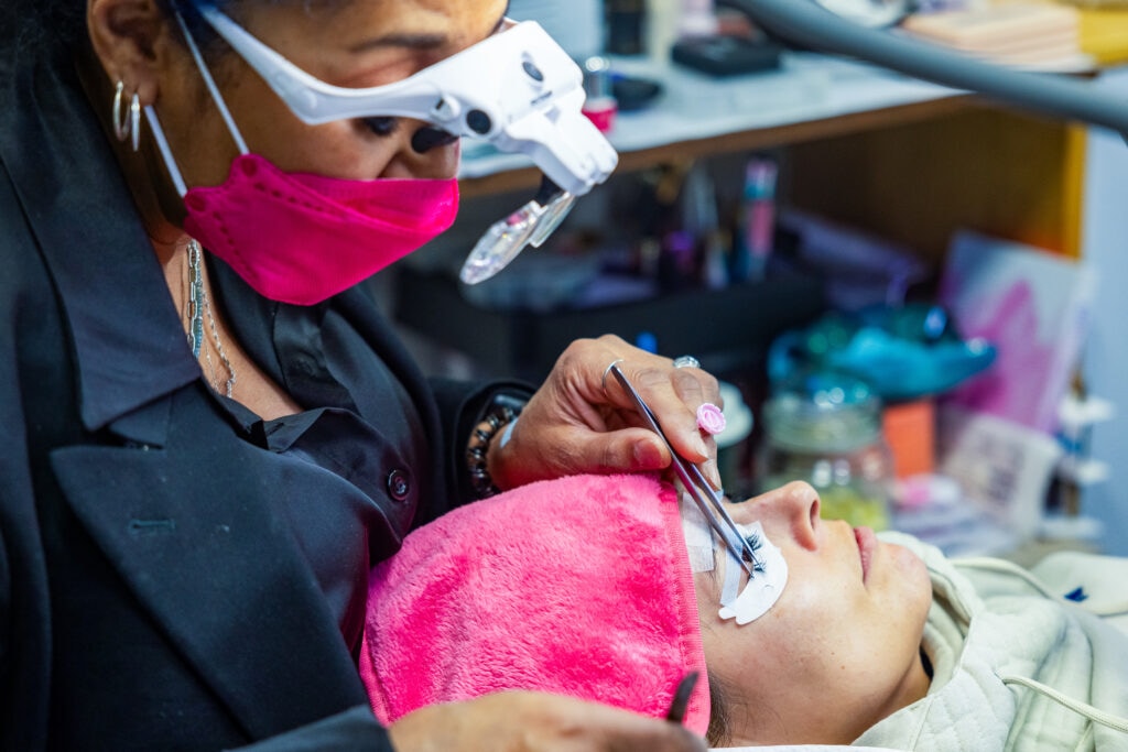 Eyelash extensions being applied at beautician's salon.