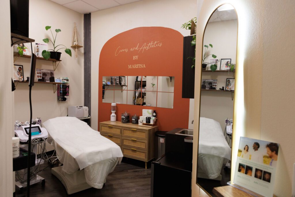 Aesthetic treatment room with bed and mirror.