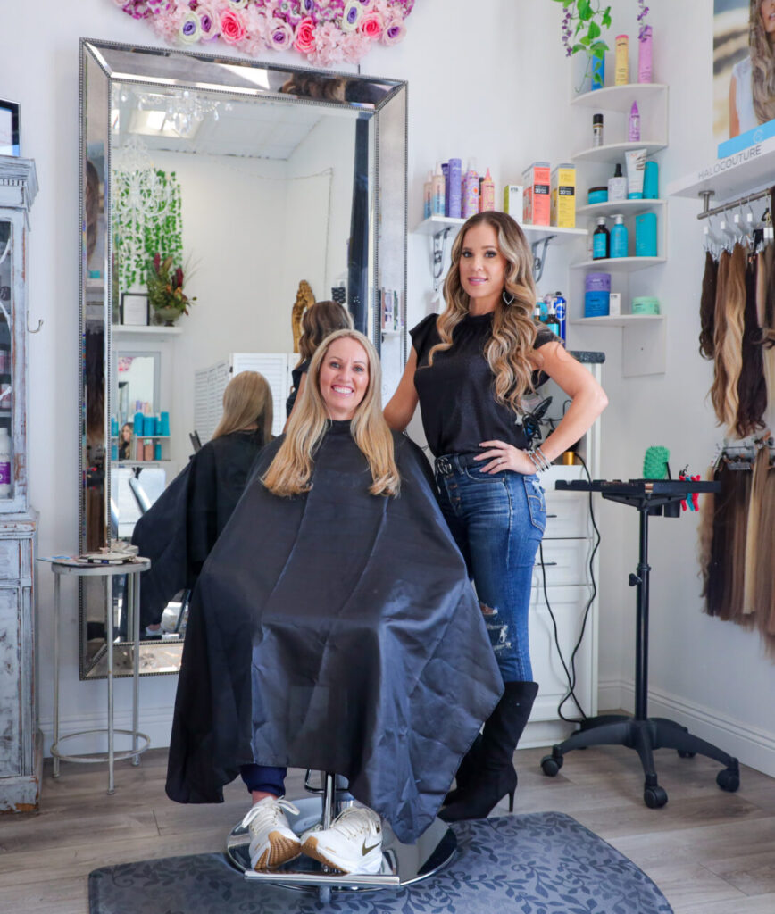 Woman in salon chair, hairstylist standing beside.