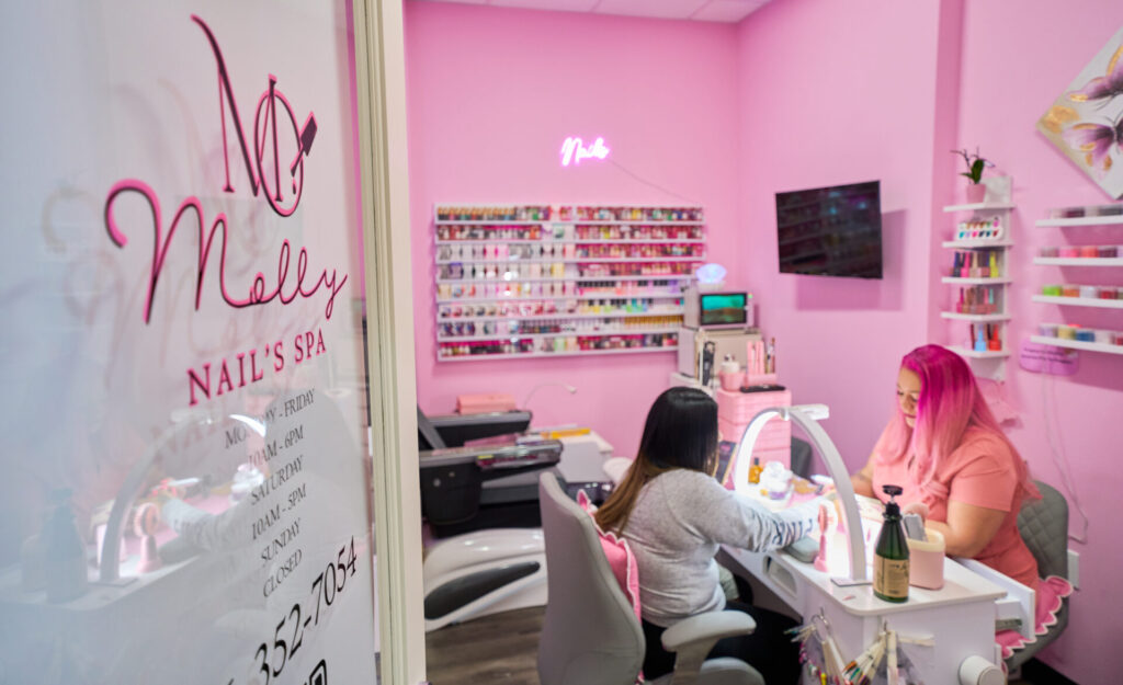 Woman getting nails done at pink spa.