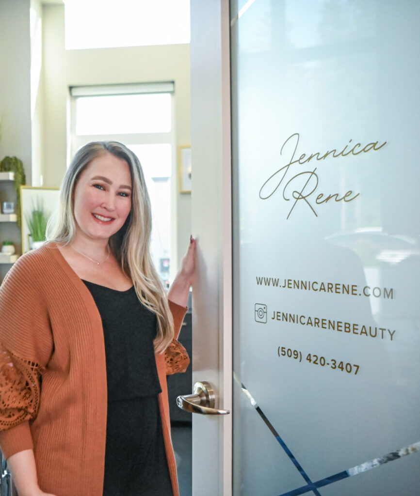 Woman standing by a glass door with company logo.