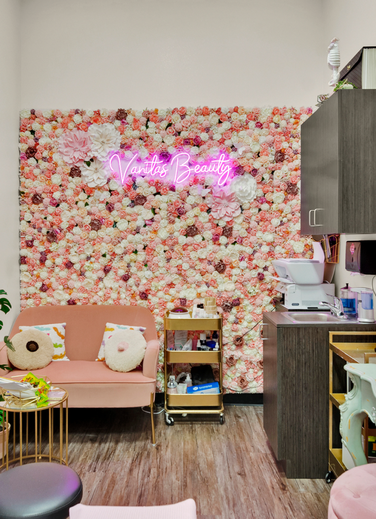 Beauty salon with floral wall and cozy seating.