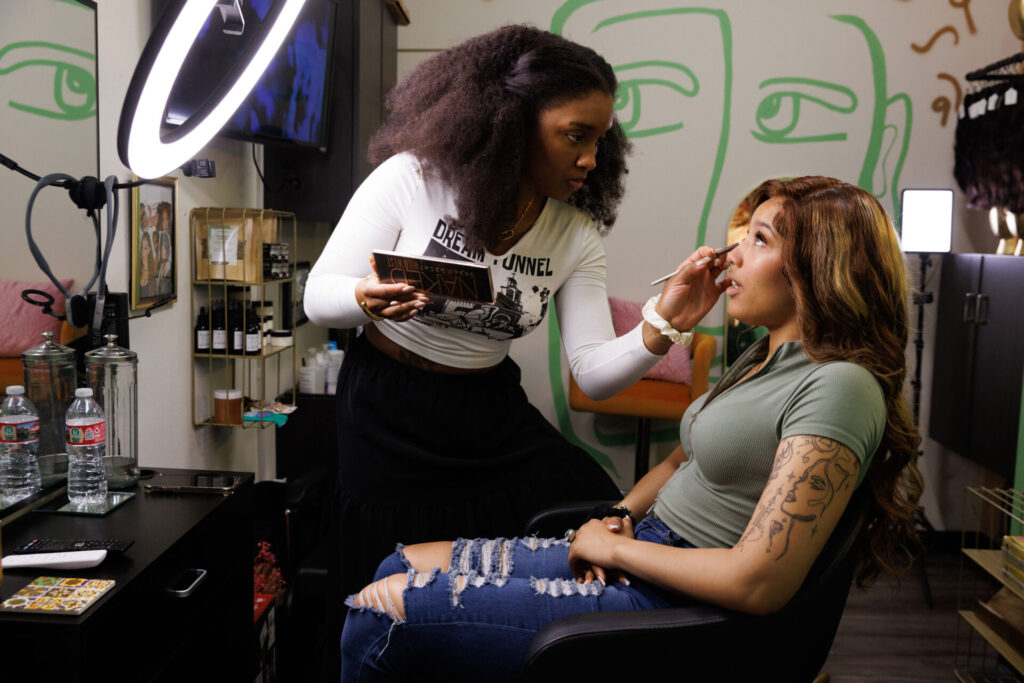 Makeup artist applying eyeshadow to client's eyes.
