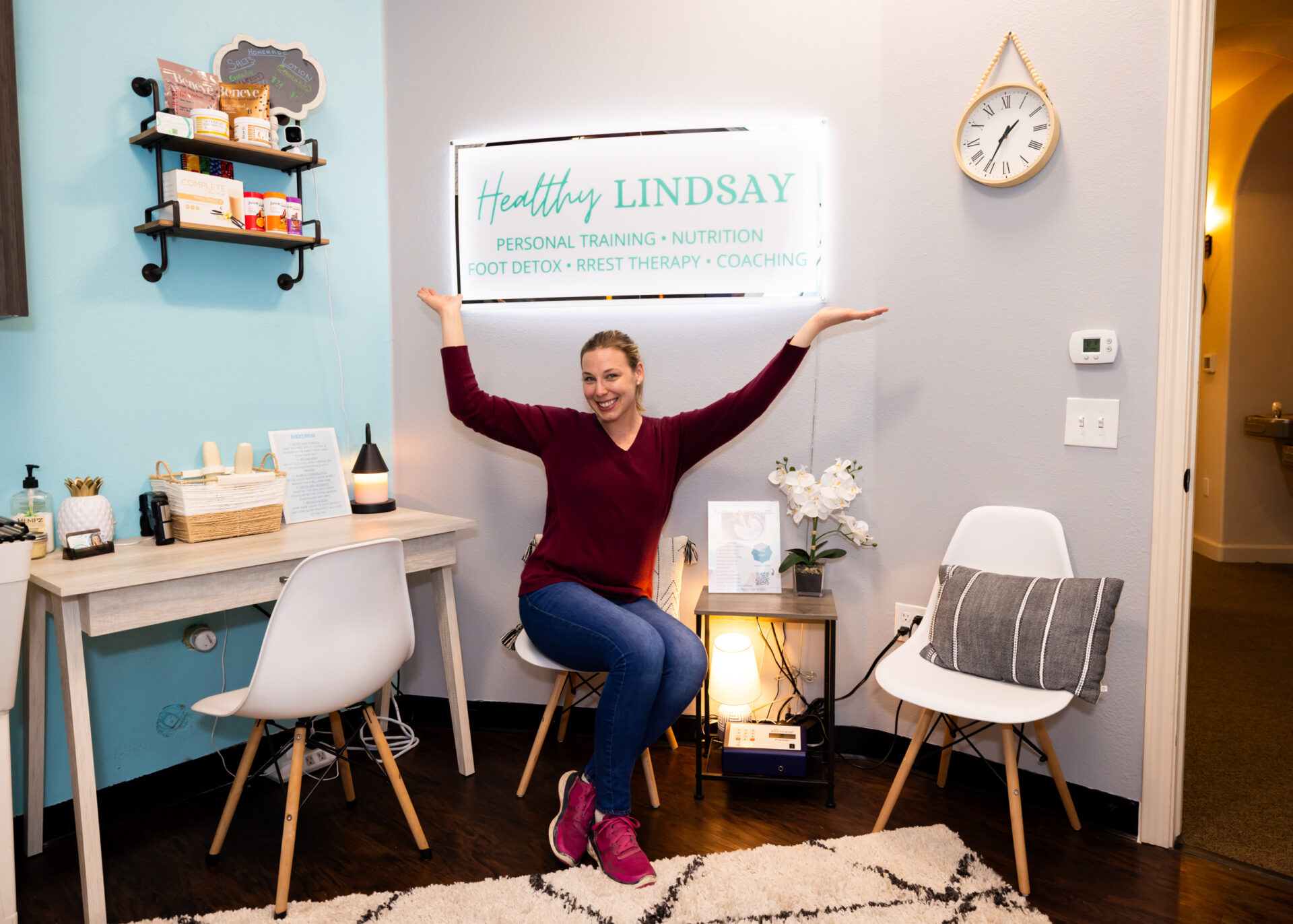 Smiling woman in wellness office displaying sign.