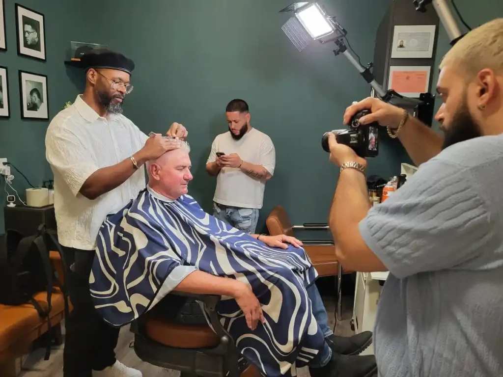 Barber cutting hair while photographer captures scene