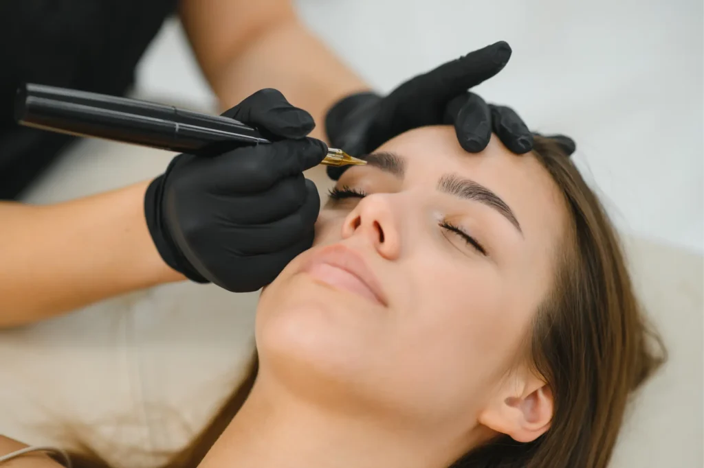 Cosmetic artist applying eyebrow tattoo treatment