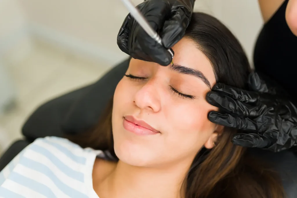 Woman receiving eyebrow tattooing treatment