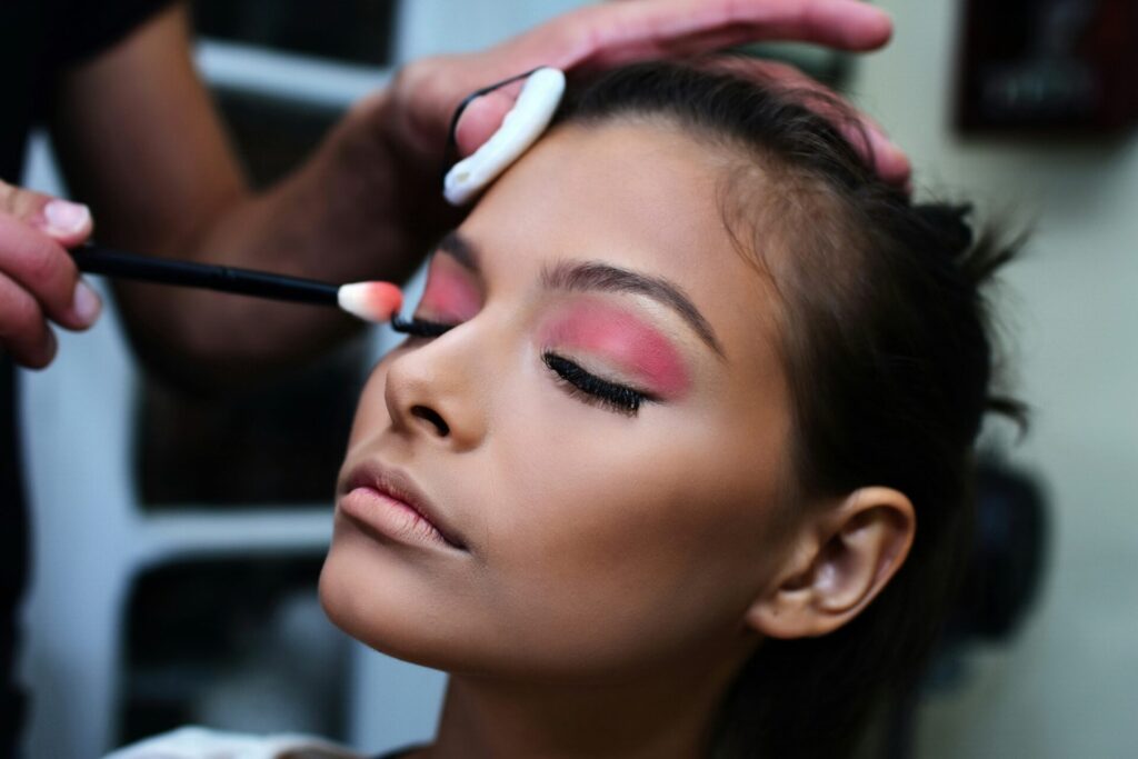 Makeup artist applying pink eyeshadow on woman