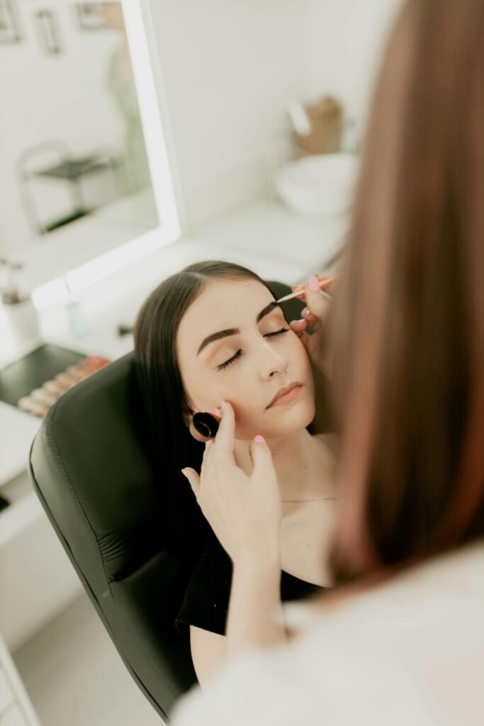 Woman receiving professional eyebrow shaping in salon.